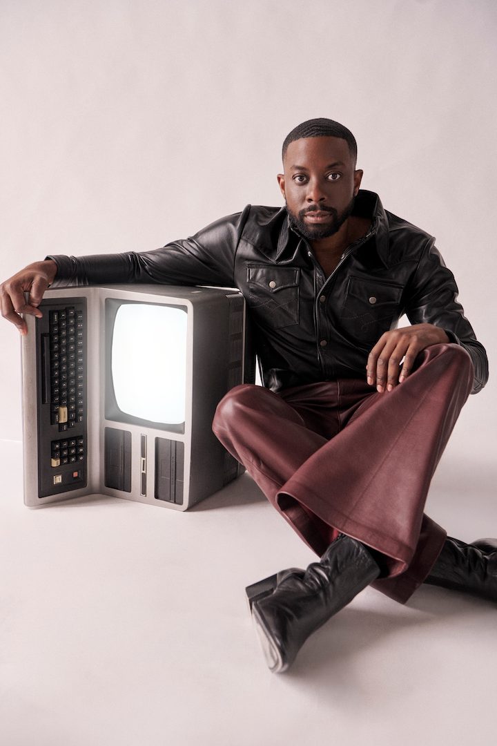 John Imah seated beside a vintage television